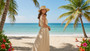 Lifestyle portrait of the Sun N Sand HH3476 Women’s Tapered Flat Top Hat in natural-toned woven straw, featuring a decorative shell-embellished hatband and a structured flat crown for an adjustable fit with UPF 50+ sun protection