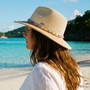 Lifestyle portrait of the Sun N Sand HH3499 Women’s Safari Hat in natural-toned woven straw, featuring a navy blue and white striped hatband and a structured fedora crown for an adjustable fit and UPF 50+ sun protection.