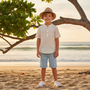 Lifestyle beach shot of the Sun N Sand HK576 Kids’ Straw Fedora in natural tan with a multi-colored embroidered band, featuring a classic indented crown and protective mid-sized brim for stylish sun protection during seaside outings and beach adventures.