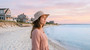 Lifestyle profile portrait of the Sun N Sand HH3600 Women’s Bucket Hat in a stone-colored tech fabric, featuring side ventilation eyelets, a matching chin cord with a toggle slider, and a structured, wide down-sloping bucket brim for an adjustable fit and UPF 50+ sun protection.