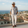 Lifestyle full-body view of the Sun N Sand HTT1282 men's straw fedora in Natural, featuring a blue and white striped grosgrain band and a structured pinched crown for refined coastal style and sun protection during resort vacations.