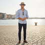 Lifestyle full-body view of the Sun N Sand HTT1283 men's straw fedora in Natural and Navy, featuring a striped red, white, and blue grosgrain band and a contrasting navy bound brim for sophisticated European style and sun protection during city travel.