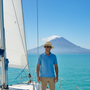 Lifestyle front view of the Sun N Sand HTT1293 men's straw fedora in Natural, featuring a brown and white patterned fabric band and a structured pinched crown for sophisticated resort style and breathable sun protection while outdoors.