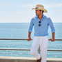 Lifestyle three-quarter view of the Sun N Sand HTT1320 men's straw western hat in Natural, featuring a blue patterned fabric hatband and a ventilated cattleman crown for sophisticated coastal style and breathable sun protection while overlooking the ocean.