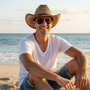 Lifestyle front view of the Sun N Sand HTT1326 men's straw western hat in Natural, featuring a ventilated teardrop crown and a dark braided hatband for rugged beach style and breathable sun protection while relaxing on the shore.