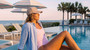 Lifestyle profile portrait of the Sun N Sand HH3663 Women’s Ball Cap in a neutral tan fabric, featuring a circular embroidered brand patch on the front and laser-perforated side panels for ventilation with an adjustable metal clasp for a custom fit and