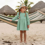 Lifestyle beach shot of the Sun N Sand HK558 kids' sun hat in a vibrant multi-color floral pattern, featuring a soft flexible brim and a crushable fabric design for easy packing and stylish UV protection.