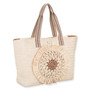 side view of light straw tote with striped handles, layered circular sunburst front detail, and textured woven body highlighting artisanal summer design.
