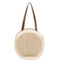 side view of round woven straw tote with radiating sunburst pattern, medium brown leather straps, and structured natural design highlighting artisanal texture.