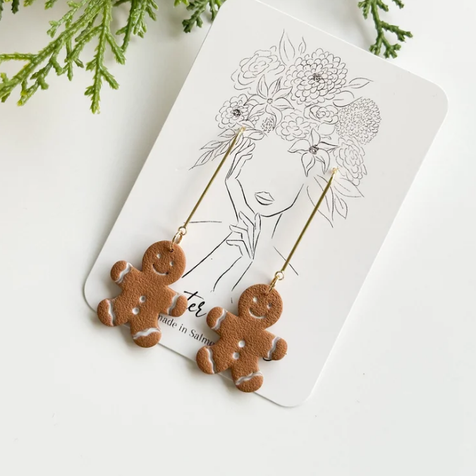 Add a dash of holiday cheer with our Gingerbread Man Dangle Earrings.

These adorable earrings feature playful, hand painted gingerbread men, complete with sweet icing details and a warm, smiling face. Hanging delicately on an ear wire, they bring a whimsical touch of festive spirit to your outfit—perfect for holiday parties, cozy gatherings, or just to add some seasonal sparkle to your everyday style.