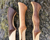 A close up three Elven style Daggers against the base of a moss covered tree trunk each with different grip styles.