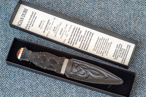 Traditional Scottish Sgian Dubh with carved Bog Oak handle, Sterling Silver fittings and Celtic Knotwork leather sheath in a black presentation box with written details of Sgain Dubh in the lid of box, including the individual serial number.