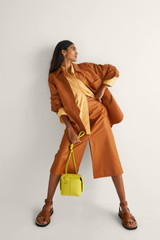 Profile view of model wearing the Oroton Leather Skirt in Tan and 100% Leather for Women