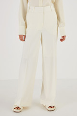 Profile view of model wearing the Oroton Flat Fronted Pant in Cream and 53% Polyester 43% Wool 4% Elastane for Women