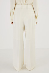 Profile view of model wearing the Oroton Flat Fronted Pant in Cream and 53% Polyester 43% Wool 4% Elastane for Women