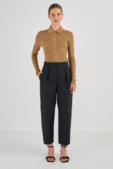 Profile view of model wearing the Oroton Pleat Curved Leg Pant in Black and 61% Cotton, 39% Polyester for Women