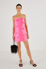 Profile view of model wearing the Oroton Satin Mini Bow Dress in Candy Pink and 85% Polyester, 15% Silk for Women
