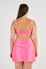 Profile view of model wearing the Oroton Satin Mini Skirt in Candy Pink and 85% Polyester, 15% Silk for Women