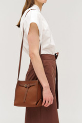Profile view of model wearing the Oroton Margot Mini Bucket Bag in Whiskey and Pebble leather for Women . IP:3