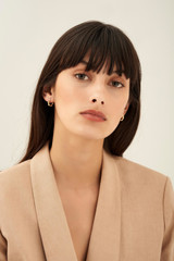 Profile view of model wearing the Oroton Bamboo Mini Hoops in Gold and Brass Base With 18CT Gold Plating for Women