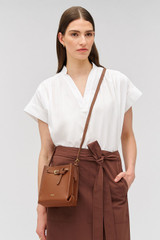 Profile view of model wearing the Oroton Margot Tiny Bucket Bag in Whiskey and Premium smooth leather for Women . IP:3
