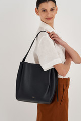Profile view of model wearing the Oroton Ingrid Hobo in Black and Pebble Leather for Women