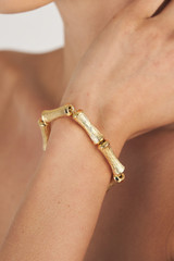 Profile view of model wearing the Oroton Bamboo Bracelet in Gold and Brass Base With 18CT Gold Plating for Women