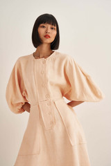 Profile view of model wearing the Oroton Sculptured Dress in Pale Mango and 100% Linen for Women