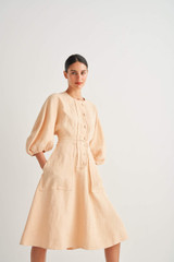 Profile view of model wearing the Oroton Sculptured Dress in Pale Mango and 100% Linen for Women