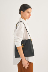 Profile view of model wearing the Oroton Tate Hobo in Black and Pebble Leather for Women