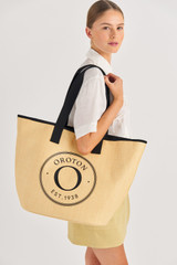 Profile view of model wearing the Oroton Kaia Straw Shopper Tote in Natural/Black and Straw for Women