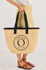 Profile view of model wearing the Oroton Kaia Straw Shopper Tote in Natural/Black and Straw for Women