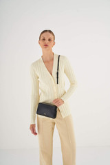 Profile view of model wearing the Oroton Inez Chain Crossbody in Black and Shiny Soft Saffiano for Women . IP:2