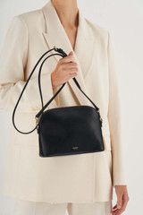 Profile view of model wearing the Oroton Inez Slim Crossbody in Black and Shiny Soft Saffiano for Women . IP:4