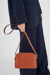 Profile view of model wearing the Oroton Inez Slim Crossbody in Cognac and Shiny Soft Saffiano for Women . IP:4