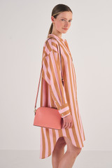 Profile view of model wearing the Oroton Inez Slim Crossbody in Pink Clay and Shiny Soft Saffiano for Women
