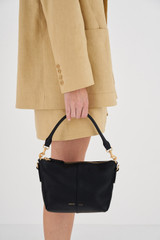 Profile view of model wearing the Oroton Lilly Zip Top Crossbody in Black and Pebble leather for Women