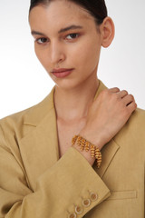 Profile view of model wearing the Oroton Riley Bracelet in Worn Gold and Brass Base With 18CT Gold Plating for Women . IP:2