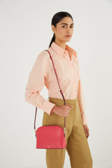 Profile view of model wearing the Oroton Inez Slim Crossbody in Peony Pink and Shiny Soft Saffiano for Women