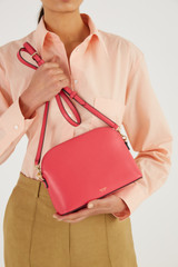 Profile view of model wearing the Oroton Inez Slim Crossbody in Peony Pink and Shiny Soft Saffiano for Women