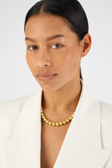 Profile view of model wearing the Oroton Bowman Necklace in Worn Gold and Brass base metal for 