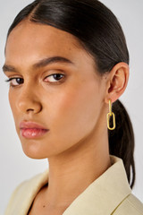 Profile view of model wearing the Oroton Isla Link Charm Hoop in Worn Gold and Brass for Women
