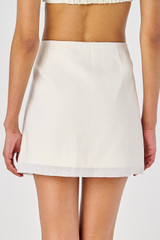 Profile view of model wearing the Oroton Lace Flower Mini Skirt in Soft Cream and sheer organdy: 100% Cotton 
skirt base: 100% Linen for Women