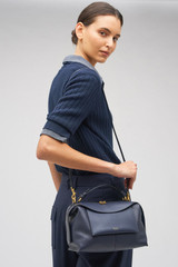 Profile view of model wearing the Oroton Mica Bowler in North Sea and Premium pebble grain leather for Women . IP:3