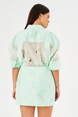 Profile view of model wearing the Oroton Lace Mini Skirt in Sea Spray and 100% polyester for Women .