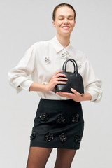 Profile view of model wearing the Oroton Flower Sequin Mini Skirt in Black and 100% linen for Women