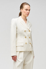 Profile view of model wearing the Oroton Shaped Double Breasted Blazer in Milk and 53% polyester, 42% virgin wool, 5% elastane for Women
