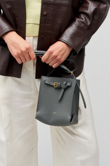 Profile view of model wearing the Oroton Margot Tiny Bucket Bag in Dark Slate and Pebble leather for Women . IP:2
