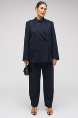 Profile view of model wearing the Oroton Tapered Pinstripe Pant in North Sea and 95% WOOL 5% ELASTANE for Women . IP:8