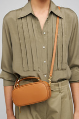 Profile view of model wearing the Oroton Margot Camera Bag in Dark Camel and Smooth Leather exterior for Women